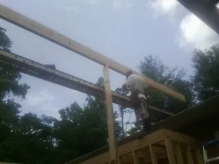 Carpenter setting a ridge beam over a new addition frame — Ice Dam Removal by Roofing Brothers in Brush Creek