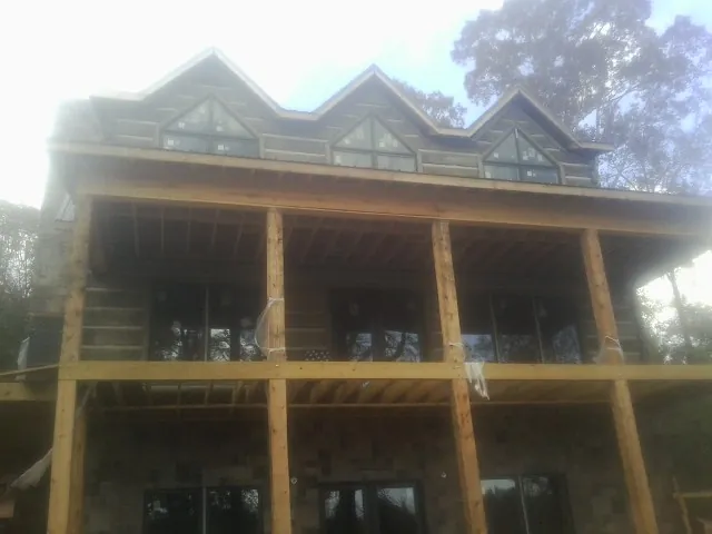 Dormers and porch framing on a large log home under construction — Roof Coating work by our crew in Brush Creek