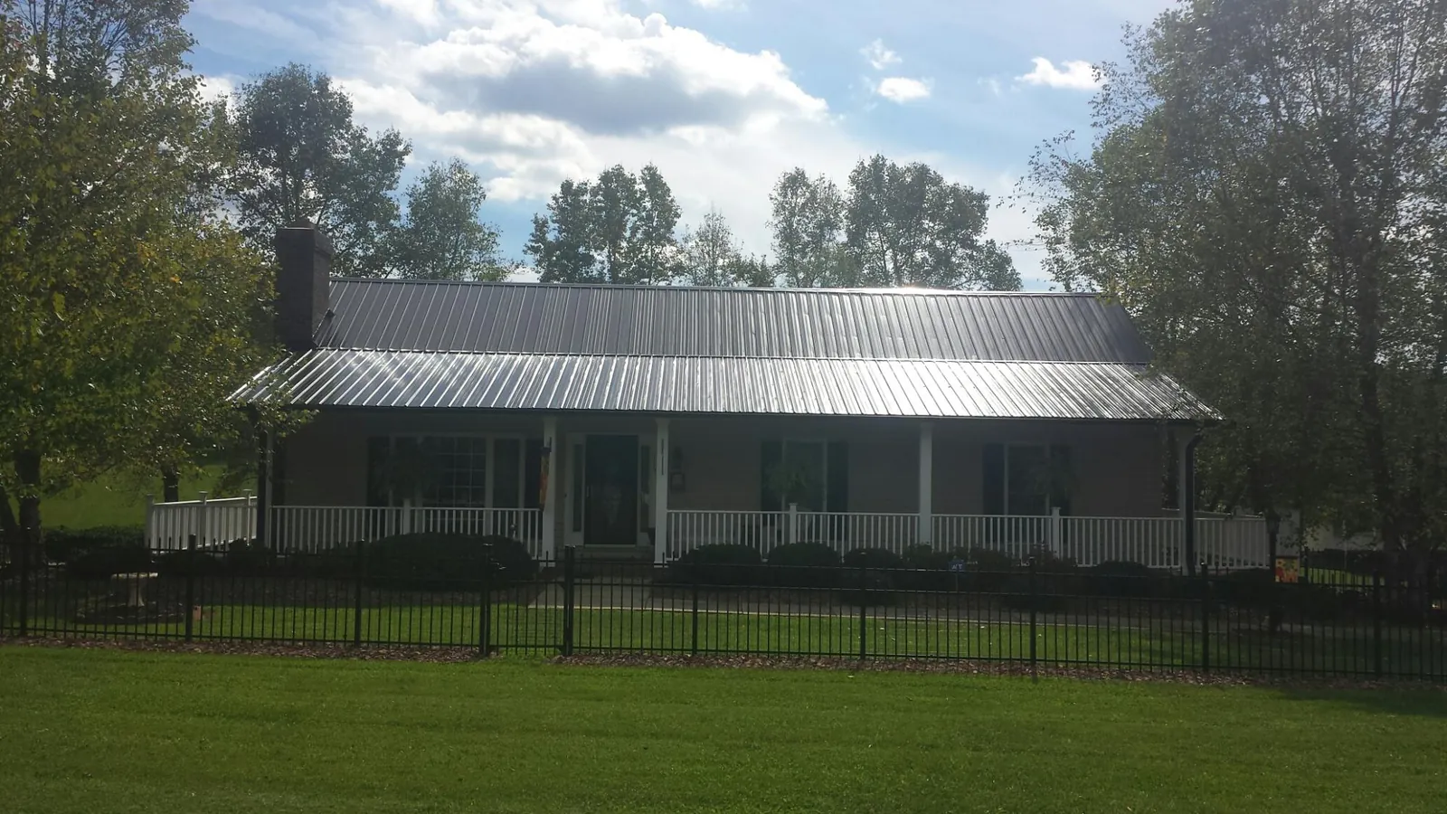 Gray metal roof on a brick ranch with a full width front porch — Gutter Guard Installation work by our crew in Brush Creek