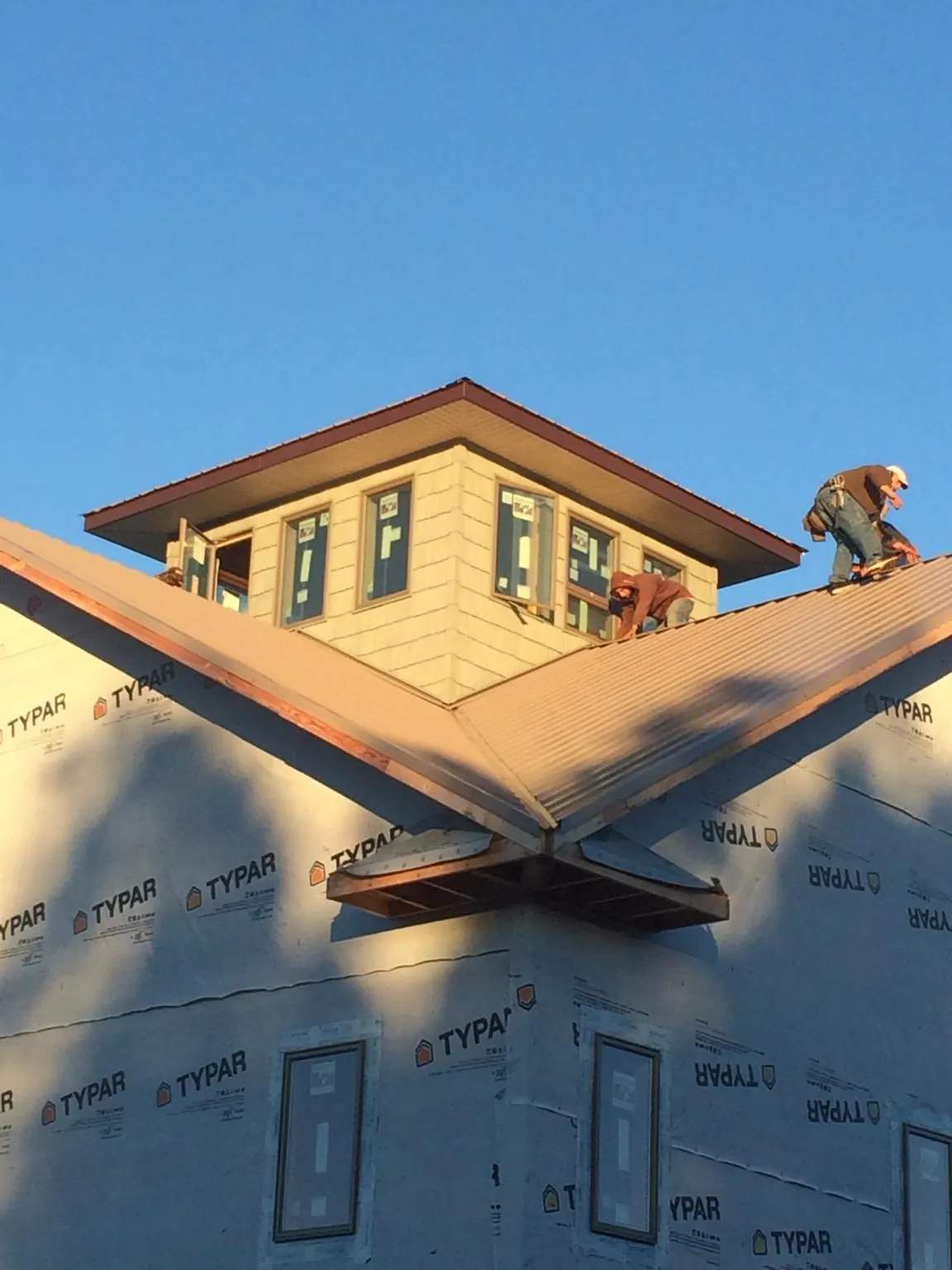Roofers working around a rooftop cupola on a new metal roof at sunset — Roof Waterproofing in Brush Creek by Roofing Brothers